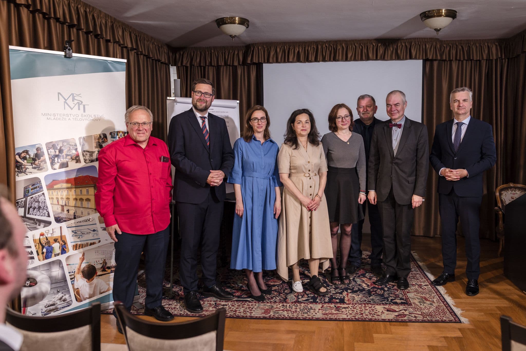 Skupinová fotografie účastníků akce u banneru Ministerstva školství, mládeže a tělovýchovy